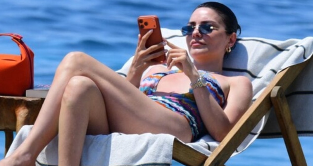 Hazal Filiz Küçükköse Bodrum plajında renkli mayoyla güneşlenirken şezlongda görülüyor.